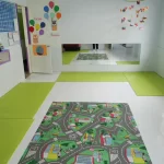 Área onde os professores ficam com os bebês engatinhando e se olhando no espelho e se divertindo com brinquedos e onde são estimulados a começarem a dar os primeiros passinhos.