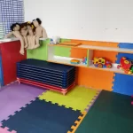 Área com tapete de quebra cabeça e com brinquedos para o lazer e diversão dos bebês do berçário do Colégio Mirassol.