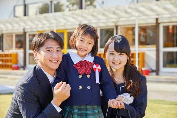 pai e mãe oriental abraçando sua filha em frente a uma escola